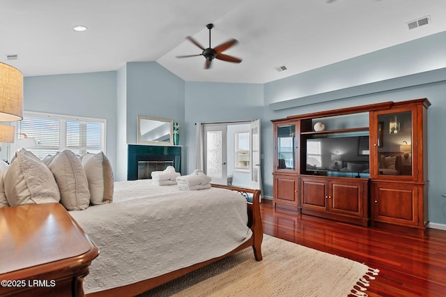 bedroom with vaulted ceiling, dark wood-type flooring, a tiled fireplace, baseboards, and recessed lighting