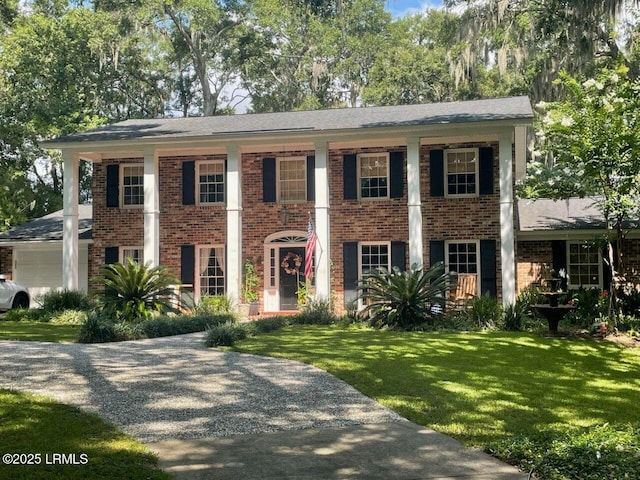 view of front of home with brick siding, an attached garage, gravel driveway, and a front yard