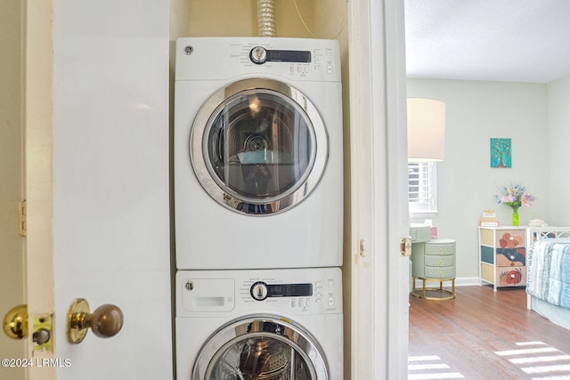 clothes washing area featuring hardwood / wood-style flooring and stacked washer and clothes dryer