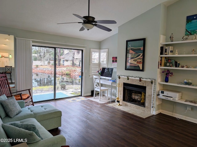 living room with a tile fireplace, vaulted ceiling, ceiling fan, a textured ceiling, and light hardwood / wood-style flooring