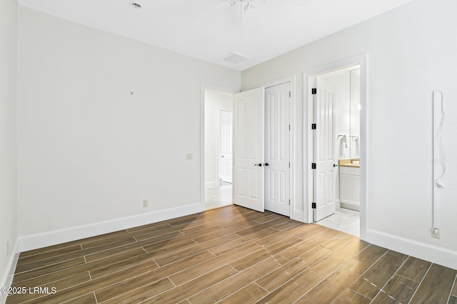 unfurnished bedroom with visible vents, wood finished floors, baseboards, and ensuite bathroom