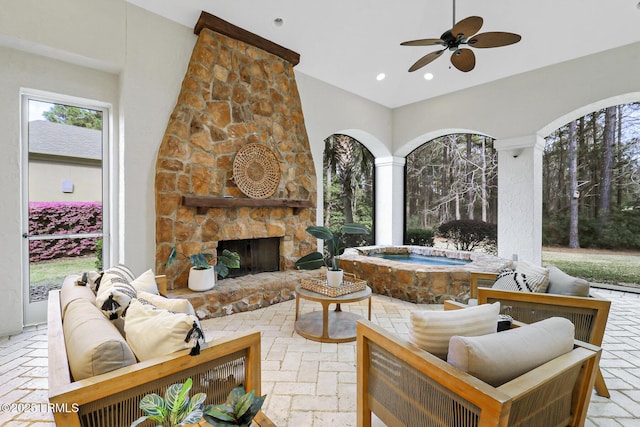 view of patio / terrace with an indoor in ground hot tub, a ceiling fan, and an outdoor living space with a fireplace