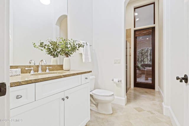 bathroom featuring toilet, vanity, and baseboards