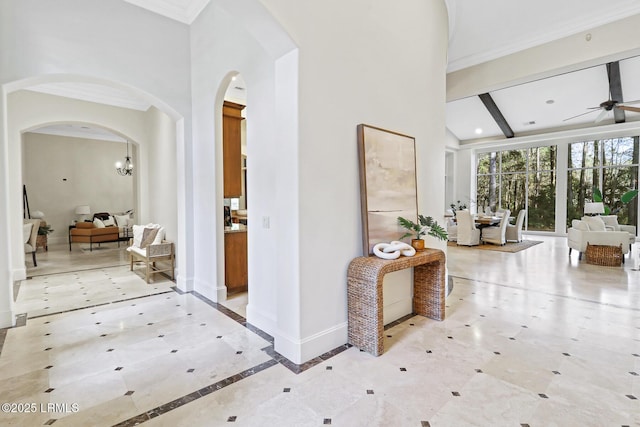 corridor with baseboards, arched walkways, and beam ceiling