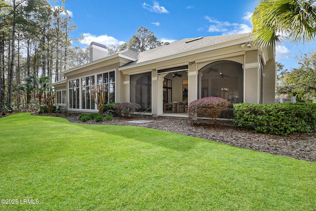 back of property featuring ceiling fan, stucco siding, a lawn, a chimney, and a sunroom