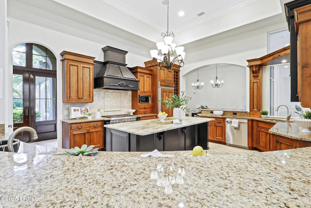 kitchen featuring crown molding, light stone countertops, a chandelier, custom range hood, and stainless steel appliances