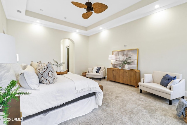 carpeted bedroom with visible vents, a ceiling fan, a tray ceiling, recessed lighting, and arched walkways