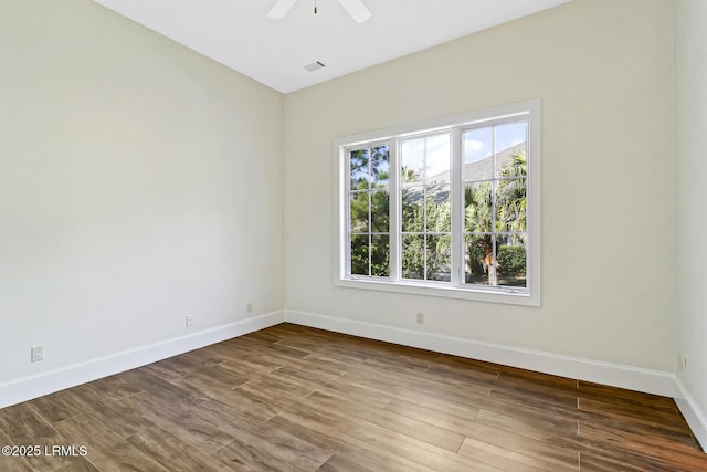 spare room featuring a ceiling fan, visible vents, wood finished floors, and baseboards