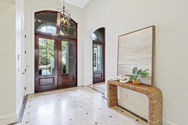 entryway with baseboards, a chandelier, arched walkways, french doors, and tile patterned floors