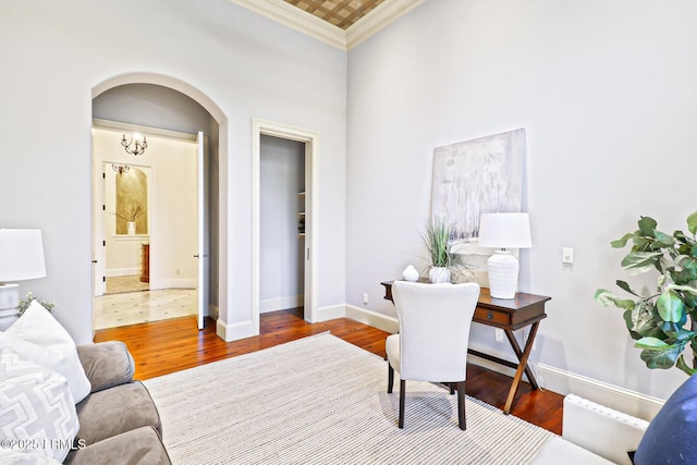 office featuring baseboards, arched walkways, wood finished floors, and crown molding