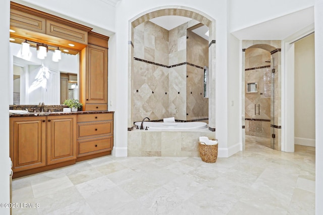 bathroom with vanity, a shower stall, a bath, and baseboards