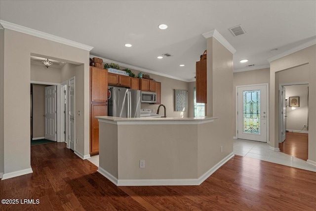 52 Summerplace Dr, Bluffton, SC 29909 - kitchen with appliances with stainless steel finishes, brown cabinetry, light wood-style floors, crown molding, and a peninsula