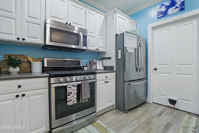 89 Bostick Cir, Beaufort, SC 29902 - kitchen with appliances with stainless steel finishes, dark countertops, white cabinets, light wood-style flooring, and crown molding