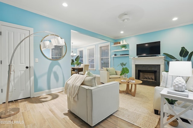 89 Bostick Cir, Beaufort, SC 29902 - living room with ornamental molding, light wood-type flooring, a fireplace with flush hearth, baseboards, and a chandelier