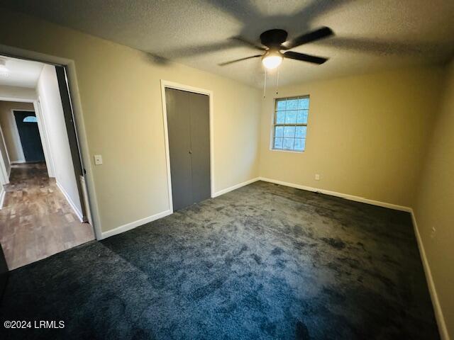 1154 Spruce St, Allendale, SC 29810 - unfurnished bedroom with dark carpet, a textured ceiling, and ceiling fan
