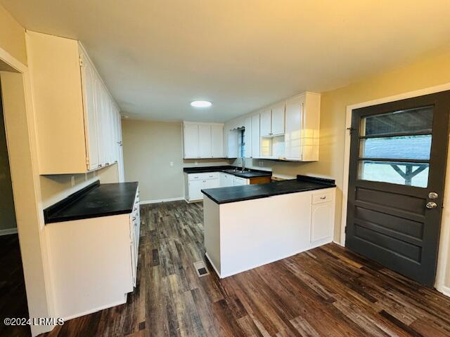 kitchen with white cabinetry, dark hardwood / wood-style floors, kitchen peninsula, and sink