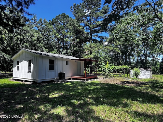 193 Paige Point Rd, Seabrook, SC 29940 - rear view of house with board and batten siding, a wooden deck, a lawn, and view of wooded area