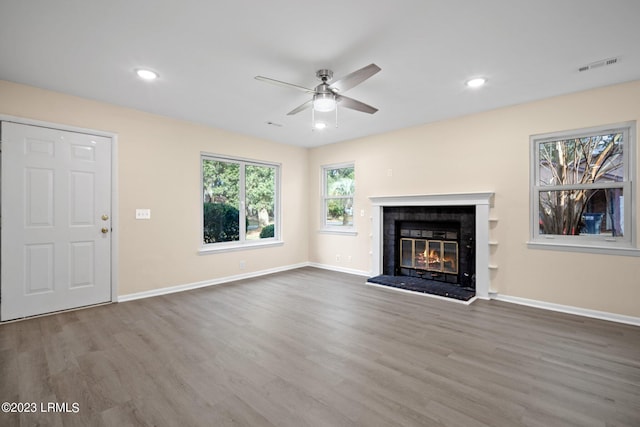 unfurnished living room with a brick fireplace, hardwood / wood-style flooring, and ceiling fan