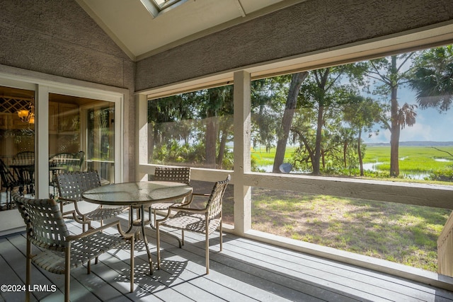 sunroom featuring a water view and vaulted ceiling with skylight