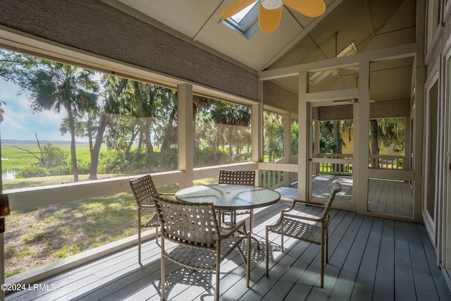 sunroom featuring a healthy amount of sunlight, ceiling fan, and vaulted ceiling with skylight