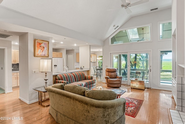 living room with high vaulted ceiling, ceiling fan, and light wood-type flooring