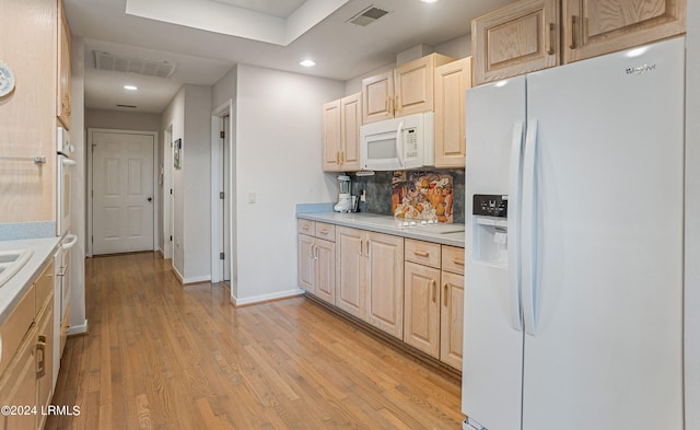 kitchen with tasteful backsplash, light wood-type flooring, light brown cabinetry, and white appliances