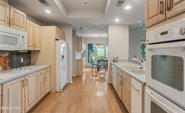 kitchen with light brown cabinetry, sink, backsplash, hanging light fixtures, and white appliances