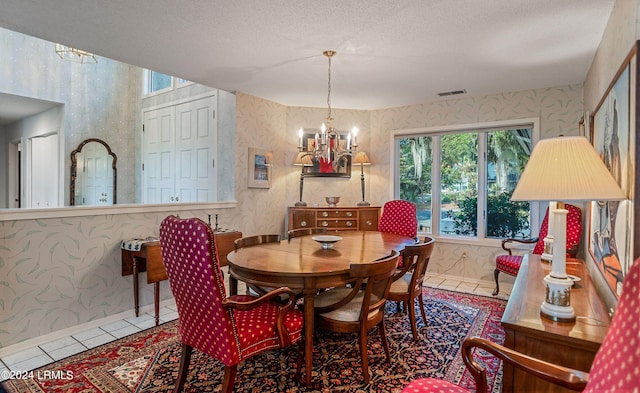 tiled dining room with an inviting chandelier and a textured ceiling