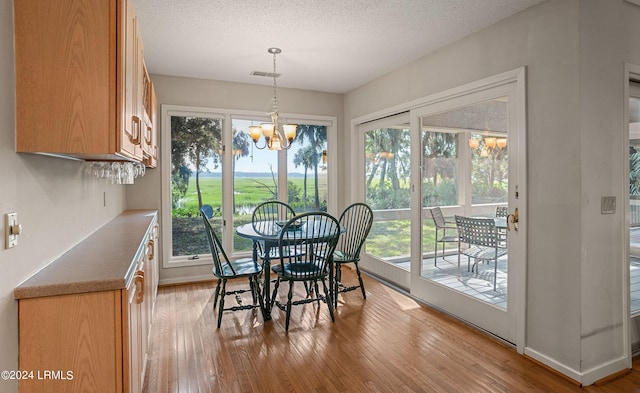 dining room featuring a notable chandelier, a textured ceiling, and light wood-type flooring