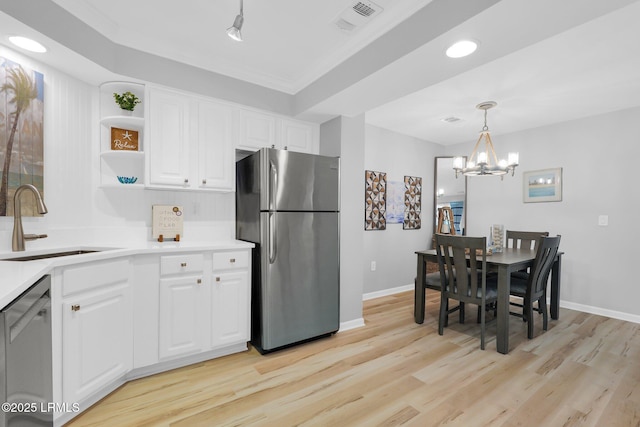 kitchen featuring sink, decorative light fixtures, light wood-type flooring, appliances with stainless steel finishes, and white cabinets