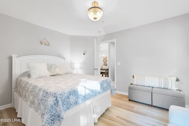 bedroom featuring an inviting chandelier and light hardwood / wood-style floors