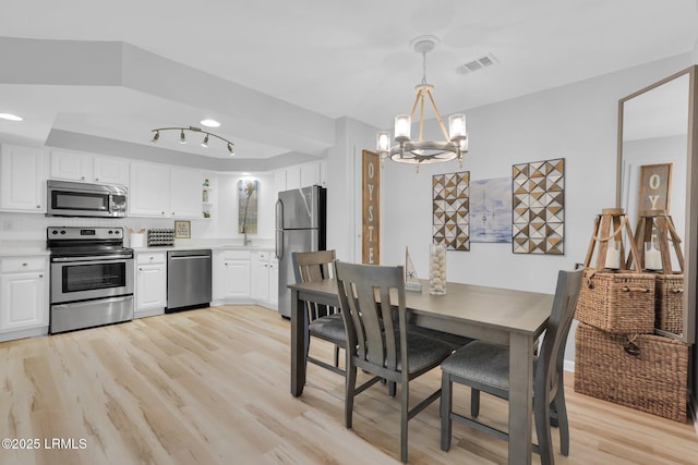 dining room featuring sink, light hardwood / wood-style flooring, and a notable chandelier