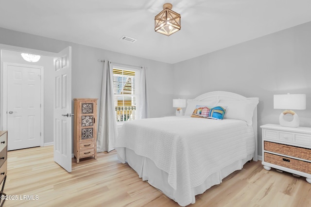 bedroom with light hardwood / wood-style flooring and a notable chandelier