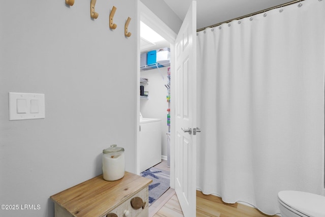 bathroom featuring hardwood / wood-style flooring, washer / dryer, and toilet