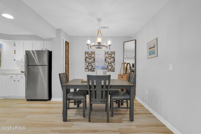 dining area with a notable chandelier and light hardwood / wood-style floors