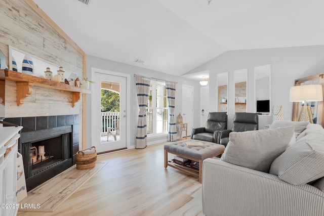 living room featuring a fireplace, vaulted ceiling, and light wood-type flooring