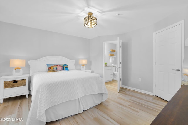 bedroom featuring connected bathroom and light hardwood / wood-style floors