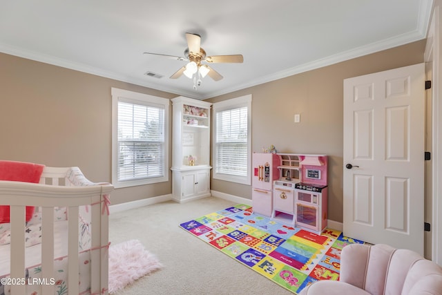 carpeted bedroom with ornamental molding, a nursery area, and ceiling fan