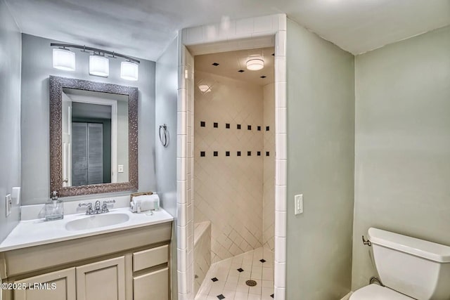 full bathroom featuring toilet, a tile shower, and vanity