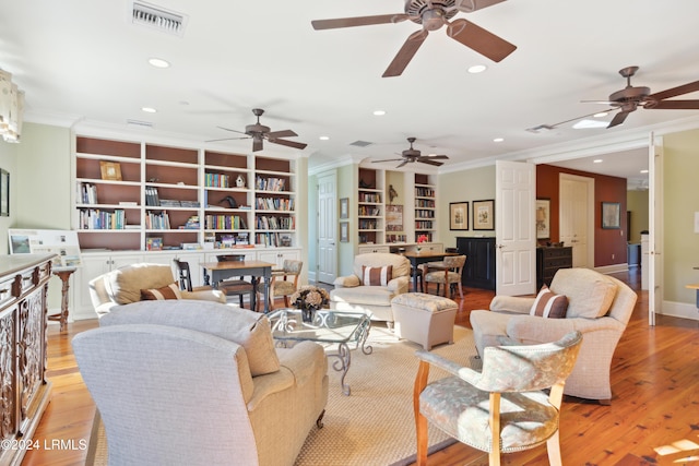 living room featuring ornamental molding, built in features, and light wood-type flooring