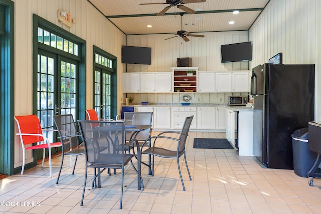 interior space featuring light tile patterned flooring, french doors, black fridge, white cabinetry, and wood ceiling