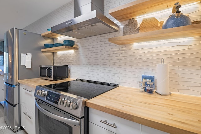 kitchen with stainless steel appliances, butcher block countertops, decorative backsplash, and exhaust hood