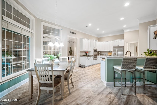 kitchen featuring stainless steel appliances, decorative light fixtures, light hardwood / wood-style flooring, and white cabinets