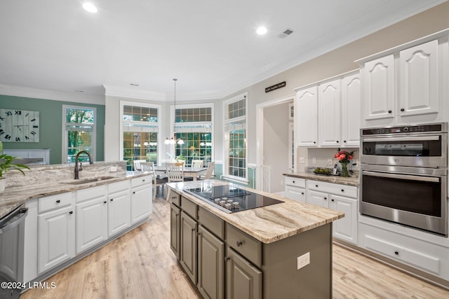 kitchen featuring stainless steel appliances, white cabinetry, a kitchen island, and sink