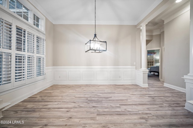 unfurnished dining area featuring crown molding, light wood-type flooring, and ornate columns