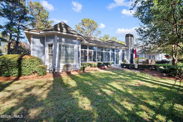 rear view of property featuring a sunroom and a lawn