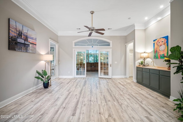 unfurnished living room with ceiling fan, ornamental molding, sink, and light wood-type flooring