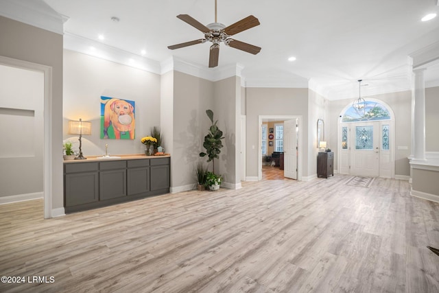 unfurnished living room featuring ornamental molding, light hardwood / wood-style flooring, decorative columns, and sink