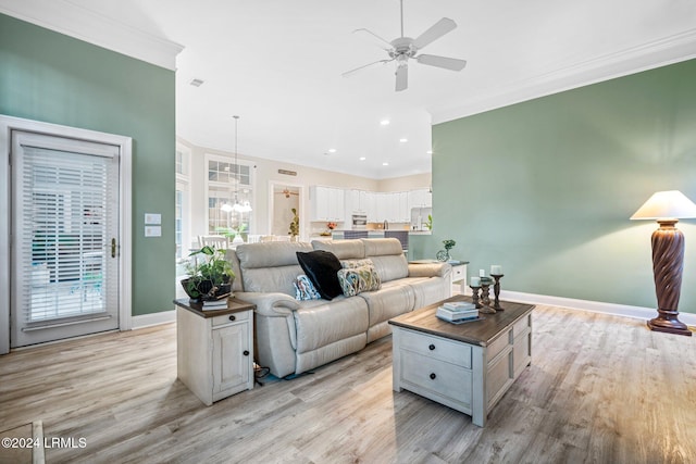 living room with ornamental molding, ceiling fan with notable chandelier, and light hardwood / wood-style floors