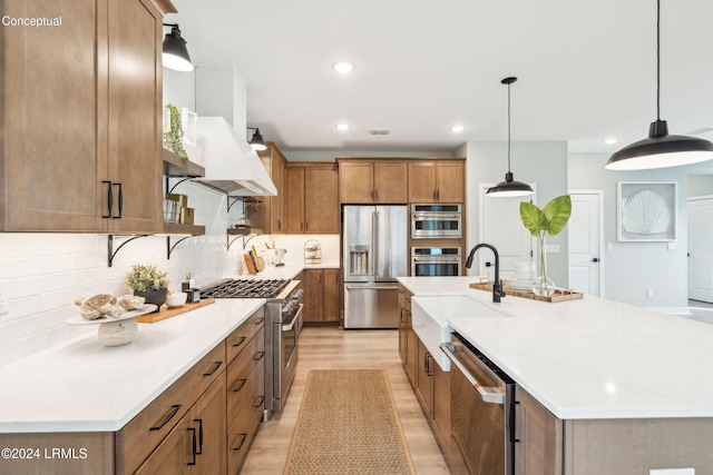 kitchen featuring decorative light fixtures, high quality appliances, sink, light hardwood / wood-style flooring, and a spacious island